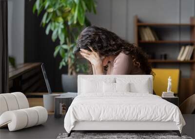 Exhausted upset woman sit at desk hide face in hands tired of difficult tasks. Stressed frustrated female employee feel headache work overtime suffer from burnout at workplace. Stressed businesswoman Wall mural