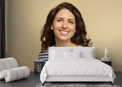 Portrait of curly caucasian female, closeup studio shot over beige background. Millennial woman with happy toothy smile and clean skin dressed in stripped t-shirt. Natural beauty and no makeup concept Wall mural