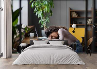 Tired businesswoman sleeping on table in office. Young exhausted girl lying on laptop keyboard, overwork unmotivated with monotonous tasks need rest. Unhappy freelancer female suffer from burnout Wall mural