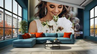 A bride in a white dress is holding a beautiful wedding bouquet. Wall mural