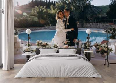 The bride and groom at the wedding table are receiving congratulations. Newlyweds by the pool. Wall mural