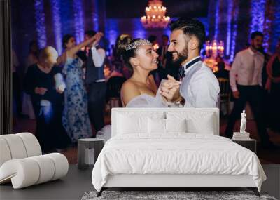 The groom invites the bride to dance. Newlyweds are dancing in a large hall. Wall mural