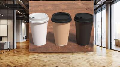 White, cardboard and black take away coffee paper cups mock up with lids on wooden background. Wall mural