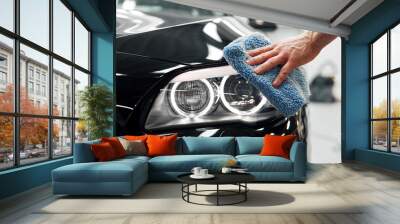 Car detailing - the man holds the microfiber in hand and polishes the car Wall mural