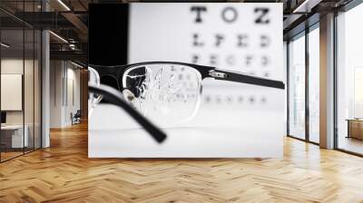 cracked glasses against the eye chart Wall mural