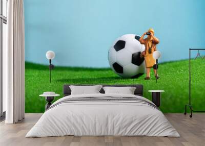 Creative photo with a soccer ball on the lawn and a tourist photographer. Wall mural