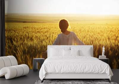 Happy woman walks over wheat field in the rays Wall mural