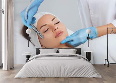 The cosmetologist makes the procedure Microdermabrasion of the face skin of a beautiful woman in a beauty salon.Cosmetology and professional skin care. Wall mural