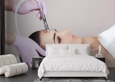 The cosmetologist makes the procedure Microdermabrasion of the facial skin of a beautiful, young woman in a beauty salon.Cosmetology and professional skin care. Wall mural