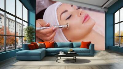 The doctor-cosmetologist makes the procedure Microdermabrasion of the facial skin of a beautiful, young woman in a beauty salon.Cosmetology and professional skin care. Wall mural