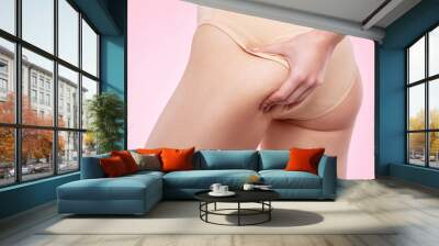 The girl stretches the skin on her leg, showing fat deposits and cellulite. The concept of weight loss and healthy lifestyle. Wall mural