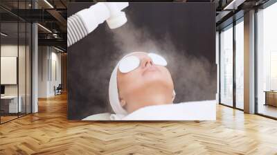 The procedure of steaming the skin of the face of a young woman before cleaning the skin in a cosmetology salon. Wall mural