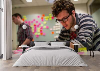 man in glasses at office working on project using colorful post-it notes. Brainstorming ideas. Work process. Wall mural