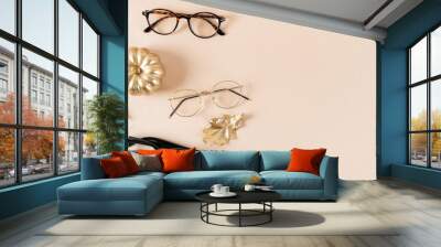 Eyewear fashion autumn collection. Trendy glasses in plastic and matallic frame on a beige background with golden leaves. Fall fashionable accessories. Optic store discount, sale. Copy space Wall mural