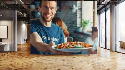 Handsome smiling male volunteer provides aid, handing out free food to disadvantaged communities indoors. Volunteers support homeless, sick, and those in poverty. Charity, donation Wall mural