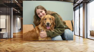 teenage girl holding her golden retriever dog pet at vet clinic for regular visit or vaccine Wall mural