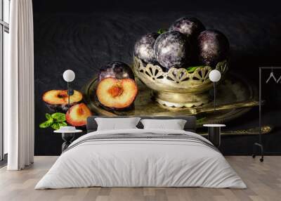 Classic still life with fresh plums placed in silver vintage plate on dark background.. Wall mural