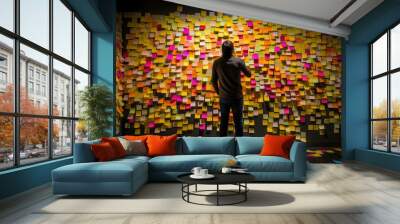 A picture of man standing in front of a wall covered in sticky notes, back view, creative concept of strategic business planning, organization of thinking.  Wall mural