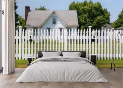 Classic white picket fence surrounds a cute country cottage. Sunny day, cozy countryside, classic exterior.  Wall mural