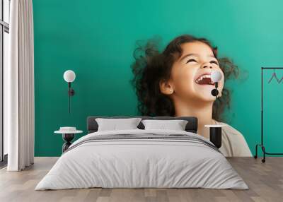 Cute junior girl laughing and smiling with curly brown hair isolated on green flat background with copy space. Happy little girl portrait. Generative AI studio photo imitation. Wall mural