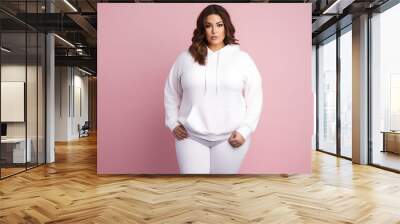 Full body portrait of plus size model woman wearing sport hoody on flat pink background, copy space. Store sportswear of all sizes, bodypositive.  Wall mural