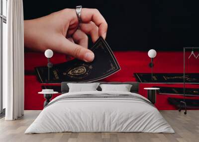 Tarot cards and hands of a fortune teller on red table background. Fortuneteller putting a tarot card on a red table. Wall mural