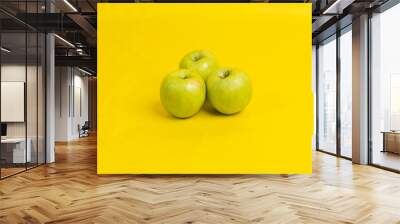 Closeup shot of three green apples on yellow background Wall mural