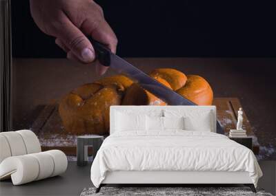 Hand is cutting fresh bread on the table with a knife Wall mural