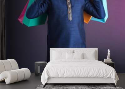 Indian traditional Young handsome man holding and posing with shopping bags on a dark background Wall mural