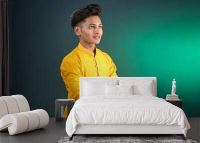 Portrait of a happy young man posing with arms crossed or hands folded on a dark background Wall mural