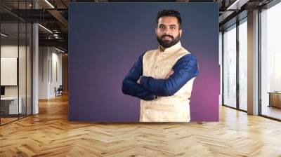 Portrait of a happy young man posing with arms crossed or hands folded on a dark background Wall mural