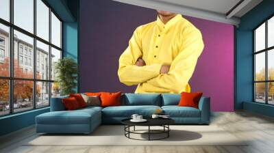 Portrait of a happy young man posing with arms crossed or hands folded on a dark background Wall mural