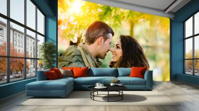 Caring young couple about to kiss under autumn tree at the park. Romantic man and woman in love. Wall mural