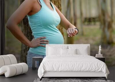 Detail of pregnant woman checking fitness workout goals on smart watch. Healthy pregnancy lifestyle concept. Wall mural