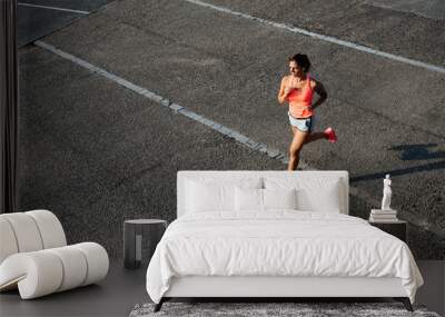 top view of woman running on city asphalt. female runner training outdoor. Wall mural