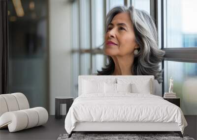 copy space, stockphoto, successful middle aged mature professional latin business woman looking out of an office window. Succesful hispanic business woman, thinking, looking outside. Wall mural