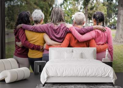 Back view of multi generational women hugging each others outdoors in city park - Focus on african woman head Wall mural