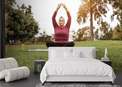 Curvy woman doing yoga meditation at city park - Focus on face Wall mural