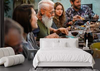 Family eating at barbecue home party dinner - Different age of people having fun at bbq meal in villa backyard - Summer lifestyle and food concept - Main focus on hipster man's face Wall mural