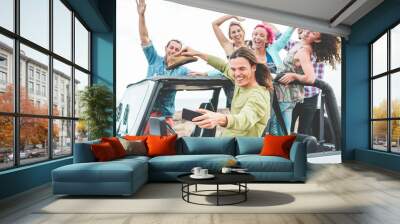 Group of happy friends doing excursion on desert in convertible 4x4 car - Young people having fun traveling together - Friendship, tour, youth and vacation concept - Focus on man taking selfie Wall mural