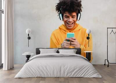 Happy african millennial guy listening music playlist with smartphone app outdoor - Young man having fun with technology trends - Tech, generation z and stylish concept - Focus on face Wall mural