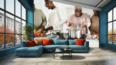 happy black family cooking vegan food inside kitchen at home - focus on mother face Wall mural