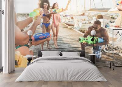 Happy friends doing battle party with water guns - Young millennials people laughing and having fum in summer vacation - Youth, lifestyle and holiday concept - Focus on left man hand Wall mural