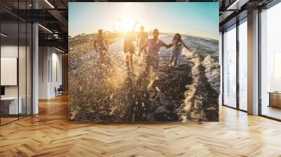 Happy friends having fun on the beach at sunset - Young people playing inside sea water outdoor in summer vacation - Friendship, youth, travel concept - Soft focus on men faces Wall mural