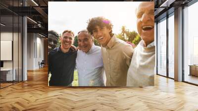 Multi generational men smiling in front of camera - Male multiracial group having fun togheter outdoor - Focus on rught boy face Wall mural