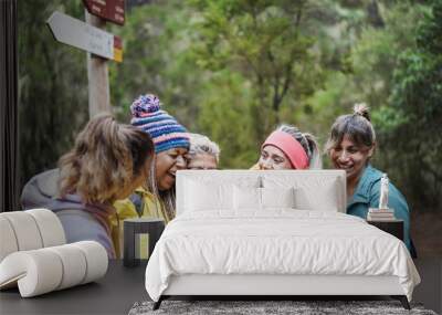 Multiracial women having fun using mobile phone for web map while trekking into the woods - Travel conept - Focus on caucasian senior face Wall mural