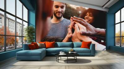 Multiracial young people celebrating together while stacking hands outdoor - Focus on hands Wall mural