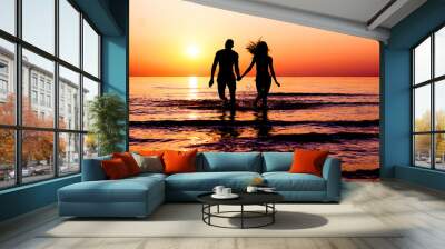 Silhouette of young fitness couple walking inside the water at sunrise - Multi race people having fun on vacation - Romantic and love concept - Soft focus on man - Sun color tones filter Wall mural