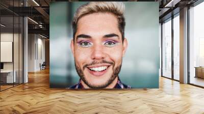 Young transgender man with makeup smiling on camera outdoor - Focus on face Wall mural