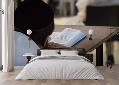 A religious man sitting and reading a torah at the Wailing Wall. Reading holy book of judaism at the western wall in Jerusalem old city. Head of the true believer in the background of the open book. Wall mural